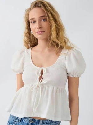 Vit blus med puffärmar och knyt - Säljer en söt vit blus med puffiga korta ärmar och knyt framtill. Blusen har en v-ringad hals och är croppad med volang nedtill. Perfekt för sommarens alla tillfällen!