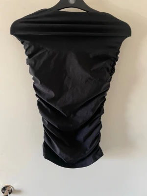 Svart kjol Fashion Nova - Säljer en svart kjol från Fashion Nova. Kjolen har en tight passform med rynkade sidor som ger en snygg siluett. Materialet är mjukt och stretchigt, perfekt för en trendig look.