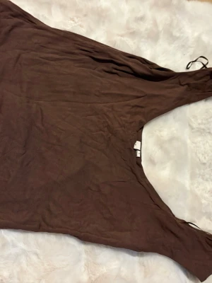 Brun ärmlös topp - En enkel brun topp i mjukt tyg med ärmlös design. Perfekt för dig som gillar minimalistisk stil och vill ha något bekvämt och snyggt. Säljer även en matchande kjol. Toppen är i storlek L men passar M