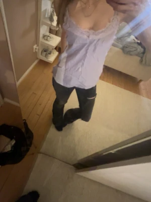 Ljuslila linnetopp från Yehwang - Säljer en söt ljuslila linnetopp från Yehwang med spetsdetaljer längs urringningen. Toppen är ärmlös och har smala axelband, perfekt för varma dagar eller lager på lager. Materialet känns lätt och luftigt.