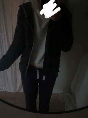 Svart pufferjacka med huva - Snygg svart pufferjacka med dragkedja och huva. Jackan har en klassisk, vadderad look och är perfekt för kyliga dagar. Passar dig som gillar en enkel och stilren stil. Jackan har ribbade muddar och en bekväm passform.