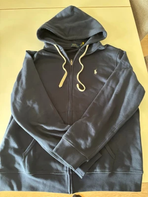 Polo ralph lauren zip hoodie - Säljer en riktigt fin Polo Ralph lauren zip hoodie som är i topp skick då den bara är andvänd 1 gång. Frågor eller funderingar är det bara att höra av dig!