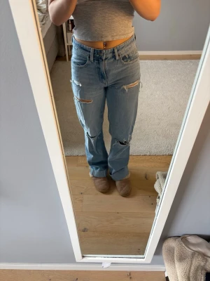 Ljusblå ripped straight leg jeans - Ljusblå jeans med raka ben och flera slitningar och hål på framsidan från Zara. Säljer pga att de ej kommer till användning, använda en gång. Långa på mig som är 162cm lång, har haft de uppvikta som på bild 5!😊