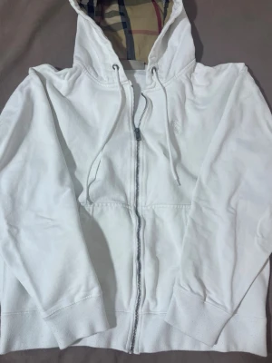Vit hoodie från Burberry med dragkedja - Snygg vit hoodie från Burberry med dragkedja och klassiskt rutigt foder i huvan. Skick 9/10🥂, passar dig som är 170-175 cm! Ni kan Järna skicka prisförslag och höras via Dm🤝
