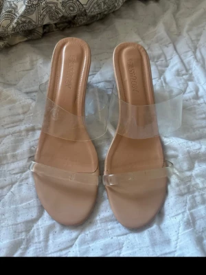 Klackskor  - Säljer ett par trendiga klackar från shein med beige sula och breda transparenta remmar. Klacken är blockformad och helt genomskinlig vilket ger en modern look. Perfekta till sommarens outfits och lätta att matcha med olika stilar. De är i storlek 40 men passar även 39