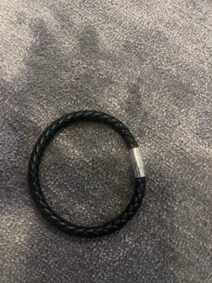 Svart flätat läderarmband - Snyggt svart armband i flätat läder med ett stilrent magnetlås i silverfärgad metall. Perfekt accessoar för dig som gillar en enkel men cool look. Passar både till jeans och t-shirt eller mer uppklätt. Längd 20,5 cm
