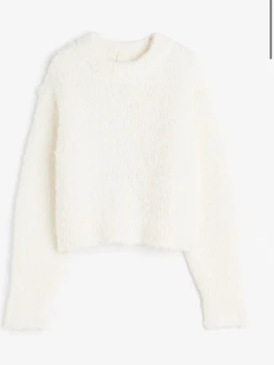 Vit fluffig stickad tröja - Mysig vit stickad tröja med fluffig textur och rund hals. Tröjan har en croppad passform och långa ärmar. Perfekt för att hålla värmen under kyliga dagar och ger en trendig look.