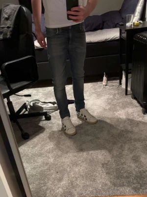 Nudie jeans - Snygga slim fit jeans i ljusblå denim från Nudie. Klassisk femficksmodell med dragkedjegylf och läderpatch bak i midjan. Jeansen har en smal passform och lätt tvättad look som ger en modern vibe. Storlek w27 L30