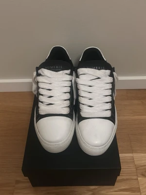Svarta och vita sneakers från Numeris - Stilrena sneakers från Numeris i svart och vitt. Skorna är i bra skick och är använda fåtal gånger. Dem tillkommer med box, väska och extra snören. Allt är originellt och skickas precis som dem gör när man beställer från hemsidan. 