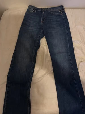 Replay  blå raka jeans - Klassiska blå jeans från Replay med rak passform och fem fickor. Jeansen har en snygg tvättad look och är tillverkade i slitstarkt denimtyg. Perfekta för en avslappnad och tidlös stil.