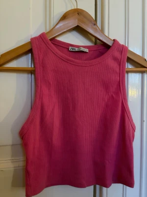 Rosa croppad ribbad topp från Zara - Säljer en rosa croppad ärmlös topp från Zara. Toppen är ribbad och har en rund halsringning. Perfekt för dig som gillar en enkel men trendig stil.