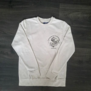 Vit sweatshirt från Jack & Jones. - Vit sweatshirt från Jack & Jones. Tryck på vänster bröst och större tryck på ryggen. Bekväm och lätt att matcha. Storlek: 164