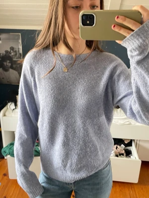 Ljusblå oversized stickad tröja - Mysig ljusblå stickad tröja med rund hals och långa ärmar. Tröjan har en oversized passform och ribbade muddar vid ärmslut och nederkant. Perfekt att matcha med jeans för en avslappnad look.