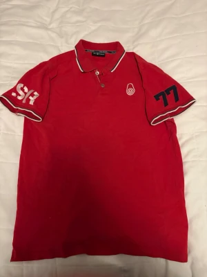 Röd Sail Racing Piké - Säljer en Röd sail racing piké med skönt material, och snygga detaljer på ärmarna och vänster bröst. Mer information är bara att fråga om.