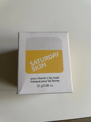 Saturday Skin Yuzu Vitamin C läppmask - Fräsch läppmask från Saturday Skin med yuzu och vitamin C. Kommer i en vit och gul förpackning, innehåller 25 g. Perfekt för att återfukta och vårda läpparna med en boost av vitaminer.