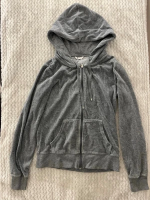 Grå zip hoodie med fickor - Klassisk grå hoodie från Cubus med dragkedja framtill, två stora magfickor och justerbar huva med snören. Tillverkad i mjukt bomullsmaterial som är skönt mot huden. Perfekt för en avslappnad och chill stil.