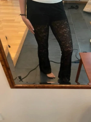 Spetsbyxor från Zar - Säljer ett par svarta leggings i genombruten spets med utsvängda ben. De har ett elastiskt midjeband och ett snyggt blommigt spetsmönster som ger en trendig look. Perfekta för dig som vill sticka ut lite extra! Klippta längst ner så det passar en som är 160 cm ungefär 
