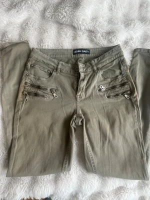 Olivgröna jeans från Denim Daisy - Olivgröna jeans i Stockholm stil, med fina silvriga detaljer. Ingen bootcut utan dragkedja nertill. Nästan helt i nyskick💓