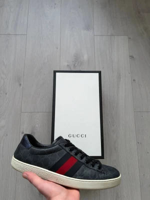 Gucci Ace Sneaker - Svarta Ace Sneakers från Gucci. Små creasingar samt liten skada på ormskinnet på hälen samt liten spricka vid creases annars helt fläckfria. Allt og tillkommer, dvs kvitto, låda, extra snören och dustbags.