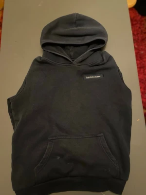 Mörkblå   hoodie Peak Performance - Mörkblå hoodie från Peak Performance med huva och magficka. Snygg minimalistisk design med liten logotyp på bröstet. Perfekt för lager-på-lager och streetwear-stil. Mjuk bomullskänsla och avslappnad passform.