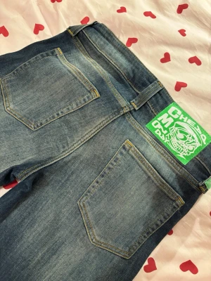 Blå jeans med grön CHEAP MONDAY-lapp - Säljer ett par blå low waist bootcut jeans från Cheap Monday i färgen Blue Ray i storleken 27/32. Använd en gång🥰