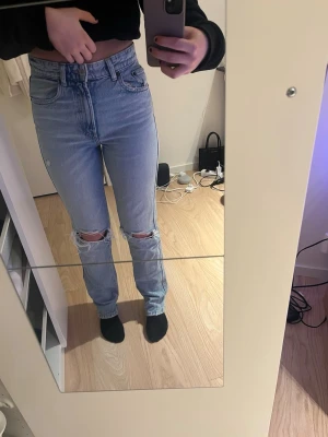 Ljusblå mom jeans med hål - Säljer ett par ljusblå mom jeans med hög midja och hål över knäna och på bakfickan. Jeansen är i väldigt bra kvalitet, har endast använd de 1-2 gånger. De är från Zara