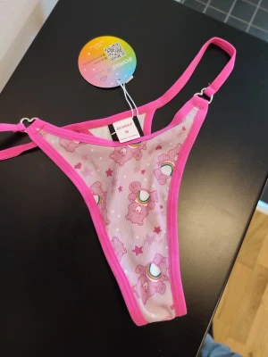 Romwe x Carebears Thong - ROMWE x CAREBEARS stringtrosa i rosa. Mjuka och stretchiga. Fina hjärtsnycken vid banden på varje sida. Storlek S. Helt nya med lapp kvar!