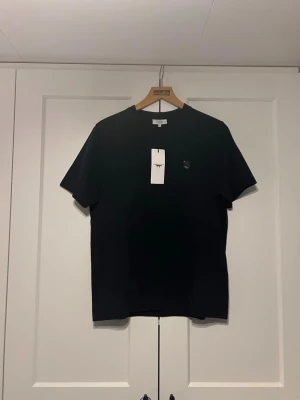 Svart t-shirt från Maison Kitsuné - Snygg svart t-shirt från Maison Kitsuné. Tröjan är aldrig använd och nypris i butik ligger på ca 1300.  Tröjan är i storlek XS men är mer oversized så den sitter mer som M. Priset är ej hugget i sten och det är bara att skriva vid fundering!!