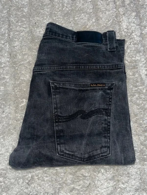 Nudie jeans  - Svarta jeans från nudie jeans i modellen Tape Ted. Jeansen har en slim passform med normal midja. Midja 41cm, längd 107cm. JAG SKICKAR INGA FLER BILDER NÄR JAG BÄR PLAGGET PÅ. För bättre inblick i passformen rekommenderar jag att googla på modellnamnet. För storleksguide kolla måtten noggrant då jeansen alltid kan vara uppsydda heller krympta och jag ej tar emot returer :) 1,65