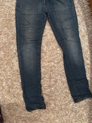 Mörkblå jeans  - Säljer ett par mörkblå skinny jeans med klassisk femficksdesign och lätt slitna detaljer på låren. Jeansen har normal passform upptill och smalnar av längs benen. Väldigt bekväma och sitter som regular fit  W33 L 32 