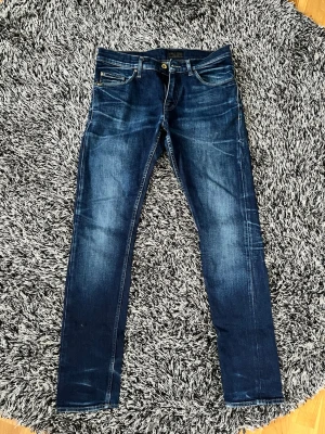 Mörkblå slim fit jeans - Säljer ett par mörkblå slim fit jeans med snygga slitningar och kontrastsömmar. Klassisk femficksmodell med dragkedja och knapp i midjan. Jeansen har en modern tvätt och raka ben, perfekta till en avslappnad stil. Skulle säga skick 8,5/10 och har inga synliga defekter. Storlek 30/32. Pris ej hugget i sten samt hör av er vid frågor.