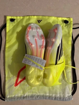 Adidas F50 gula fotbollsskor - Säljer ett par Adidas F50 fotbollsskor i en riktigt fräsch gul färg med svarta detaljer och vita inslag. Skorna har snörning, lätta material och dobbar i plast för bästa grepp på planen. Perfekta för dig som vill sticka ut och få max speed på konstgräs eller naturgräs.