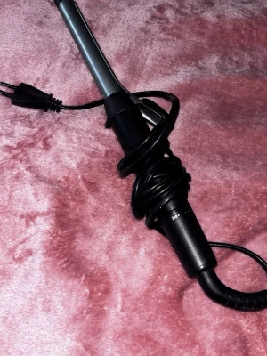 Svart locktång remington - Säljer en svart locktång med sladd och temperaturreglage upp till 210 grader. Perfekt för att styla håret med snygga lockar. Modern design i svart plast och metall. Enkel att använda och passar de flesta hårtyper. Använd 1 gång. Original lådan finns ej.