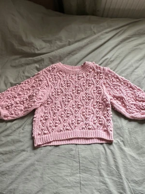 Rosa stickad tröja med puffärmar - Supersöt rosa stickad tröja med puffiga ärmar och ett detaljerat hålmönster över hela plagget. Tröjan har rund halsringning och ribbade muddar vid ärmslut och nederkant. Perfekt för dig som gillar en gullig och trendig stil. Storlek s från lindex och aldrig använd⭐️
