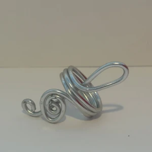 Silvrig spiralring i metall - Unik ring i silvrig metall med spiralformad design och stora, svepande kurvor. Ringen har en konstnärlig och modern look som verkligen sticker ut på fingret. Perfekt för dig som gillar statement-smycken och vill ha något annorlunda.