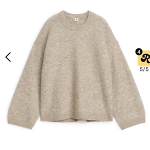 Beige stickad tröja från arket - Mysig beige stickad tröja från Arket med rund halsringning och avslappnad passform. Tröjan har långa ärmar och ribbade muddar vid hals, ärmslut och nederkant. Perfekt för lager på lager och enkel att matcha till olika outfits. nypris ca 1000kr