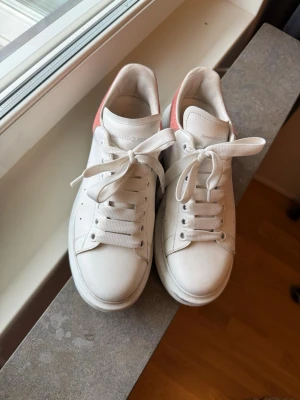Vita Alexander McQueen sneakers - Stilrena vita sneakers från Alexander McQueen med chunky sula och rosa/aprikos detalj på hälen. Fint skick måste bara tvättas lite😆älskade mina på studenten! Hör av er så kommer vi överens om köp via Plick. Låda tillkommer 