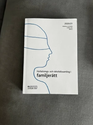 Författningssamling i familjerätt 2020/21 - Samling med författningar och rättsfall inom familjerätt, utgiven av Norstedts Juridik. Boken har vit framsida med blå linjeteckning av ett ansikte och svart text. Perfekt för juridikstudier och kurslitteratur.