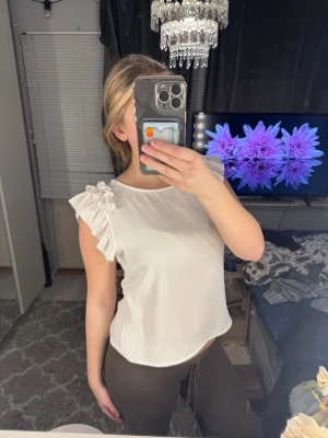 Vit blus med volangärmar - Säljer en söt vit blus med korta volangärmar. Toppen har en rak passform och är tillverkad i ett mjukt tyg som känns skönt mot huden. Köpt på Zara med tyvärr är inte lappen kvar, helt oanvänd!