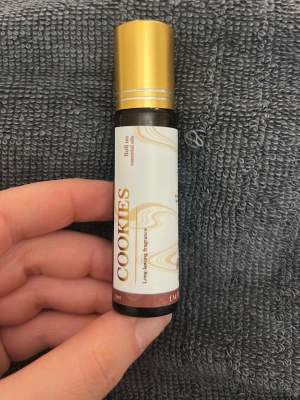 Cookies roll-on parfymolja - Säljer en roll-on parfymolja med doften Cookies. Flaskan är liten och smidig, har vit etikett med guldiga detaljer och ett guldfärgat lock. Perfekt att ha med i väskan för en söt och unik doft. 10ml oanvänd