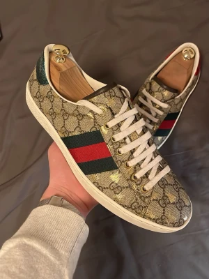 Gucci ace monogram gold bee - Hej! Säljer dessa gucci skor i storlek 42,5 (8 1/2). Fett bra skick. Nästan helt nya! Endast använda väldigt få gånger. Tvättas självklart innan köp. Nypris: 8000kr. Har allt og förutom box. Ja har gucci papper, kort, extrasnören och dustbags. Skorna är självklart äkta vilket jag står för och det är olagligt att sälja märkeskopior. Helt perfekta till sommaren och kommer vara riktigt fräscha!! Hör gärna av er! 