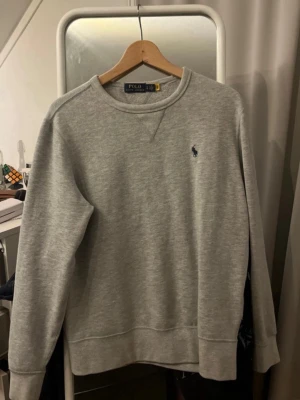 Grå sweatshirt från Polo Ralph Lauren - Säljer min gråa Ralph Lauren sweatshirt eftersom den är för liten för mig. Skicket är bra och sparsamt använd. Storleken är S eller ish 170 cm.