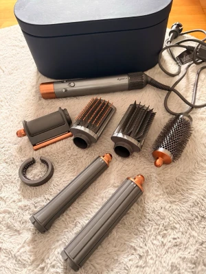 Dyson Airwrap multistyler koppar/svart - Säljer en Dyson Airwrap multistyler i koppar och svart med flera tillbehör för styling, inklusive borstar och locktillbehör. Kommer med en snygg förvaringsväska. Perfekt för att skapa olika frisyrer med ett enda verktyg. Digitalt kvitto finns ! 