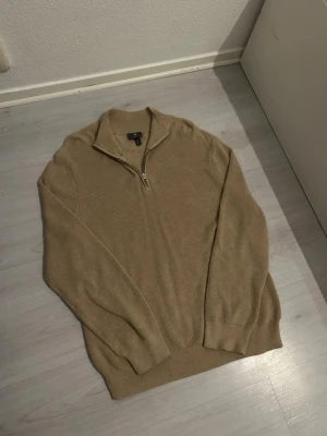 Beige stickad tröja med half zip från H&M - Stickad beige tröja från H&M med ribbad struktur och half zip-dragkedja vid kragen. Tröjan har lång ärm och en avslappnad passform, perfekt för lager på lager. Enkel och stilren design som funkar till det mesta. Har använt den 2 gånger, inga defekter eller syns att den är använd. (Storlek M) (Passform L) (100% bomull) kan minskas i tvätten. Skickar samma dag eller dagen efter 