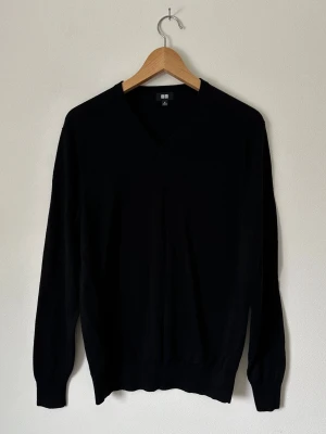 Svart V-ringad stickad tröja Uniqlo - Klassisk svart stickad tröja från Uniqlo med V-ringning och långa ärmar. Tröjan har ribbade muddar vid ärmslut och nederkant. Perfekt basplagg som funkar till allt och är enkel att styla.