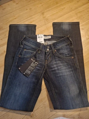 Mörkblå Lee jeans - Snygga mörkblå jeans från Lee, aldrig använda. Står ingen storlek men måtten är: midjemått: ca 30cm     innerbenslängd: ca 76cm         Bootcuten/längst ner: ca 20 cm                            