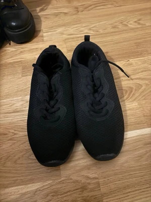 Svarta mesh sneakers med snörning - Svarta sneakers med mesh-överdel och snörning. Skorna har en låg profil och en tjock, mönstrad gummisula som ger bra grepp. Perfekt för dig som gillar en clean och enkel stil. Märke ej angivet. Nästan helt nya använda Max 3x 