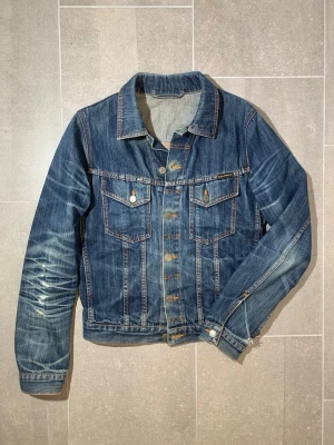 Nudie Jeans Dry indigo Denim jacket - Raw denim jacka från Nudie jeans med extrema fades. Jackan har en cropped fit och fina honeycombs. Storlek S men utgå alltid från angivna mått!                                                   Längd 62 Bredd (över bröstet) 53 Ärmlängd (från axeln) 65 