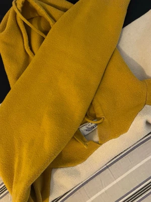 Senapsgul hoodie från Lee Hip - Cool senapsgul hoodie från Lee Hip med klassisk huva och dragsnören. Tröjan är gjord i ett mjukt material och har ribbade muddar vid ärmslut och nederkant. Perfekt för dig som vill ha en färgstark och bekväm look.