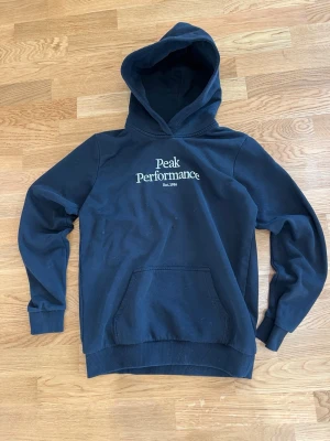 Svart hoodie Peak Performance - Tjena, säljer denna hoodie som nu är för liten för mig. Den är i storlek 170/S. Den har ett pyttelitet hål vid magen och en liten grå fläck på axeln men det går nog att fixa med fläckborttagning. Hålet går nog också ganska lätt att sy igen om man är lite händigare än mig. Skriv om du undrar något så löser vi det!